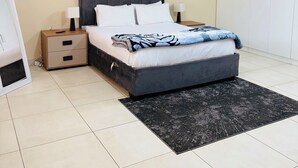 A bedroom with a bed, bedside tables, a wardrobe, and a floor lamp. - Airport Continental Guest House (Kempton Park)