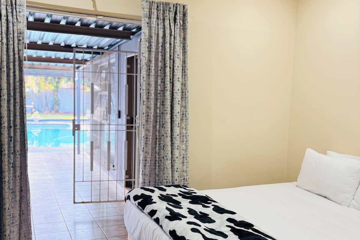 Un dormitorio con cama, vistas a una piscina y una puerta que da al exterior.