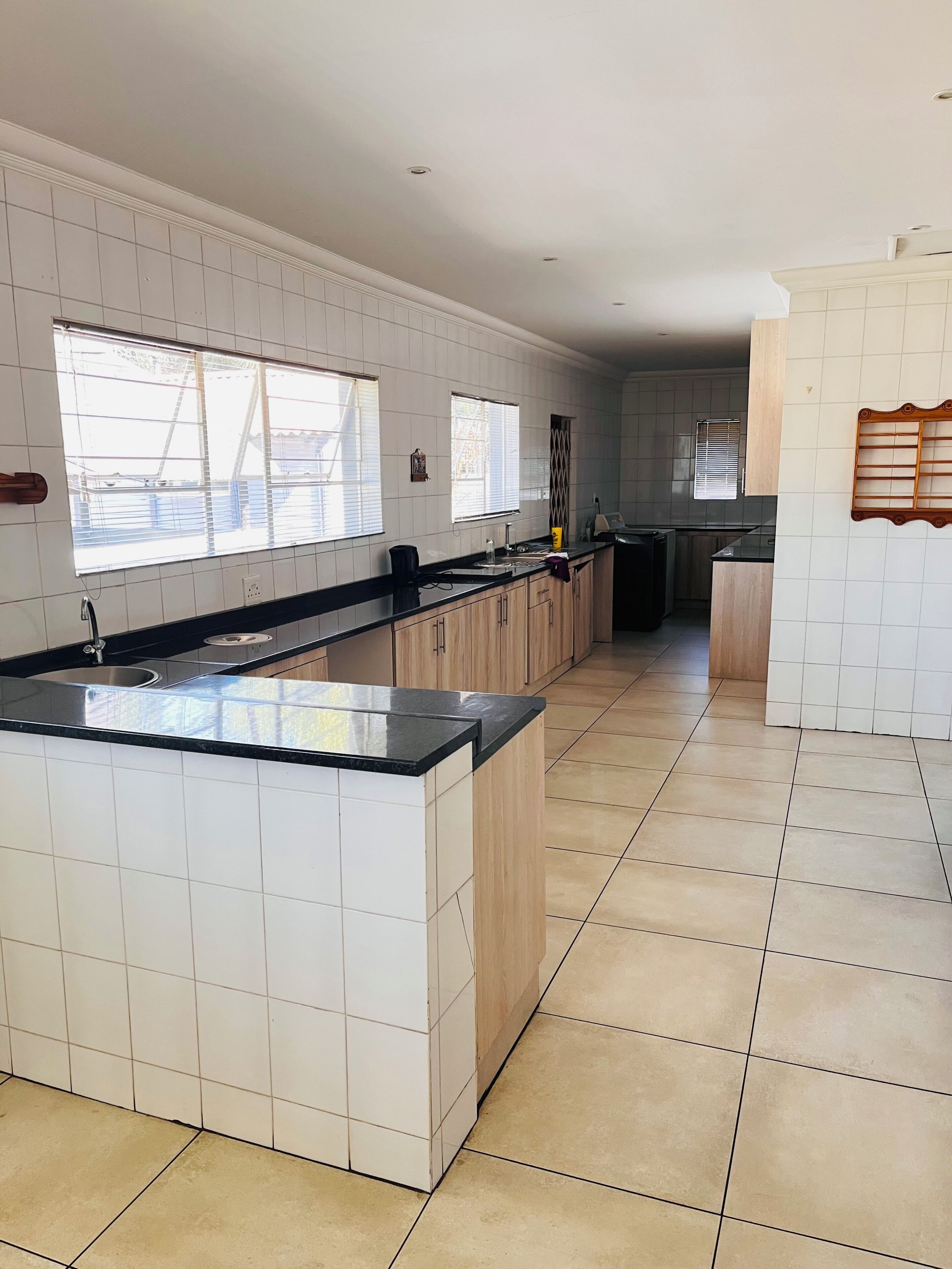 A modern kitchen with a large island, white tiled walls, and a tiled floor.