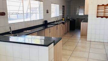 A modern kitchen with a large island, white tiled walls, and a tiled floor.