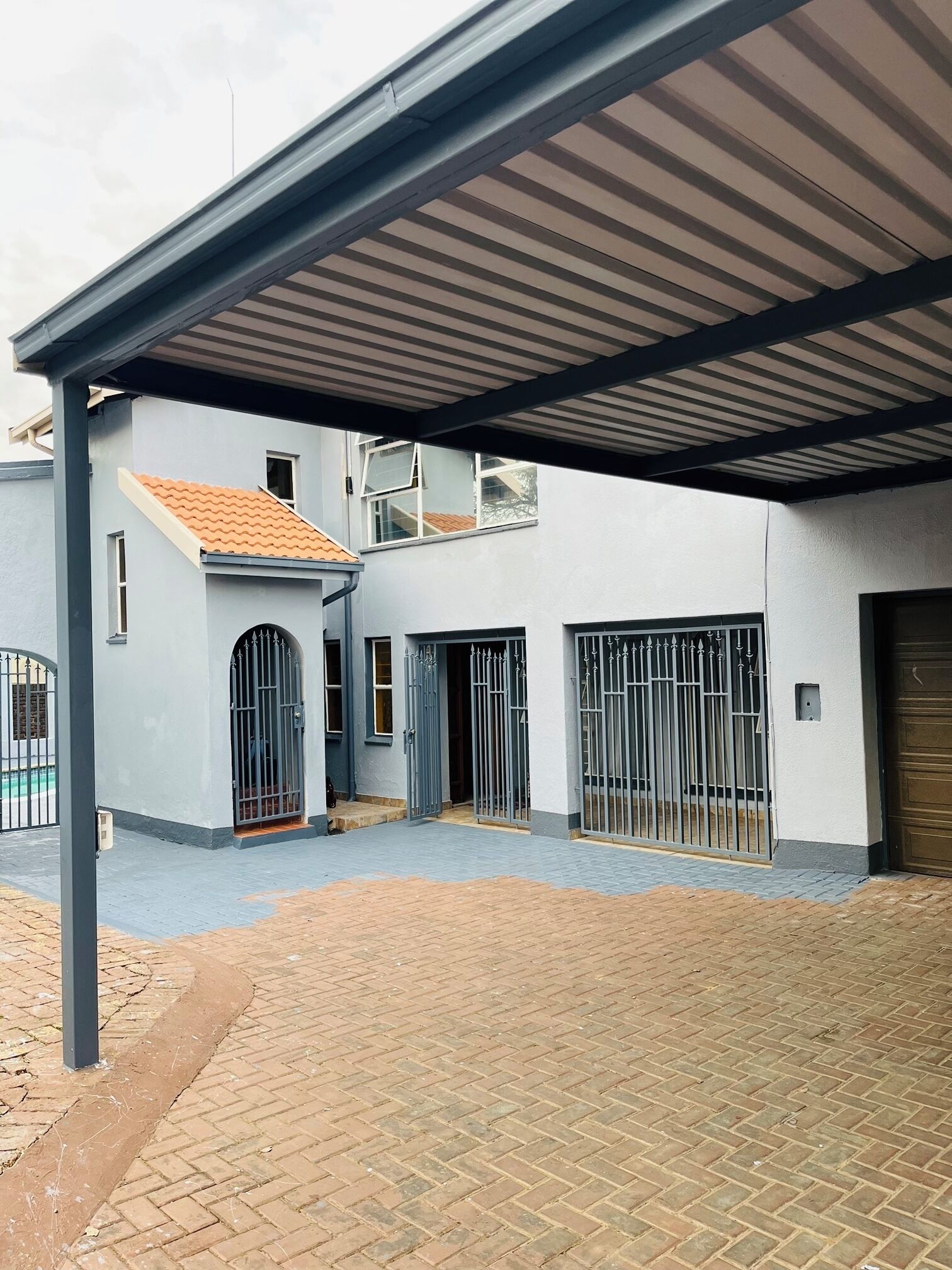 Uma área externa coberta com um edifício, uma entrada gradeada e um caminho pavimentado.