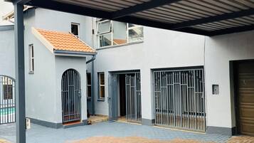 Uma área externa coberta com um edifício, uma entrada gradeada e um caminho pavimentado.