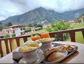 A breakfast table with eggs, toast, and juice, overlooking a mountainous landscape. - Balcón de gocta (Cocachimba)