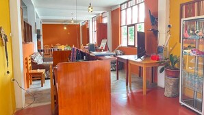 Una habitación con un escritorio de madera, una silla, una planta en maceta y un aparador de vidrio con botellas.