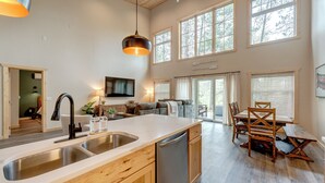 A modern kitchen with a dishwasher, double sink, and wooden cabinets. - NEW Luxury Riverfront Home, large deck, river tubing, kayaks, 5 min to Downtown (Hayward)