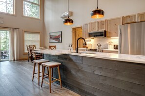 Een moderne keuken met een groot eiland, houten kastjes en hangende lampen.