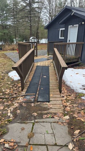A wooden deck leading to a small cabin with a white door and a window. - Serene Otter Lake Waterfront | Dock + Fire Pit (Huntsville)