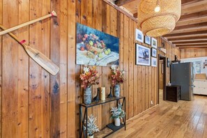 A wooden interior with a painting, a table with vases, and a ceiling light. - Serene Otter Lake Waterfront, Dock + Fire Pit (Huntsville)
