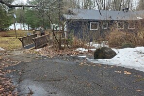 A house with a metal roof, a wooden deck, and a stone pathway leading to a dock. - Serene Otter Lake Waterfront | Dock + Fire Pit (Huntsville)