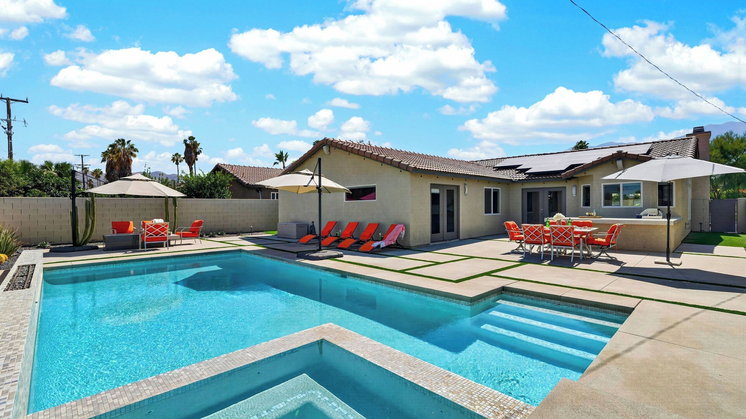 A swimming pool with a tiled deck, sun loungers, and a barbecue area.