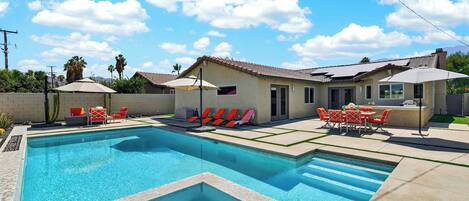A swimming pool with a tiled deck, sun loungers, and a barbecue area.
