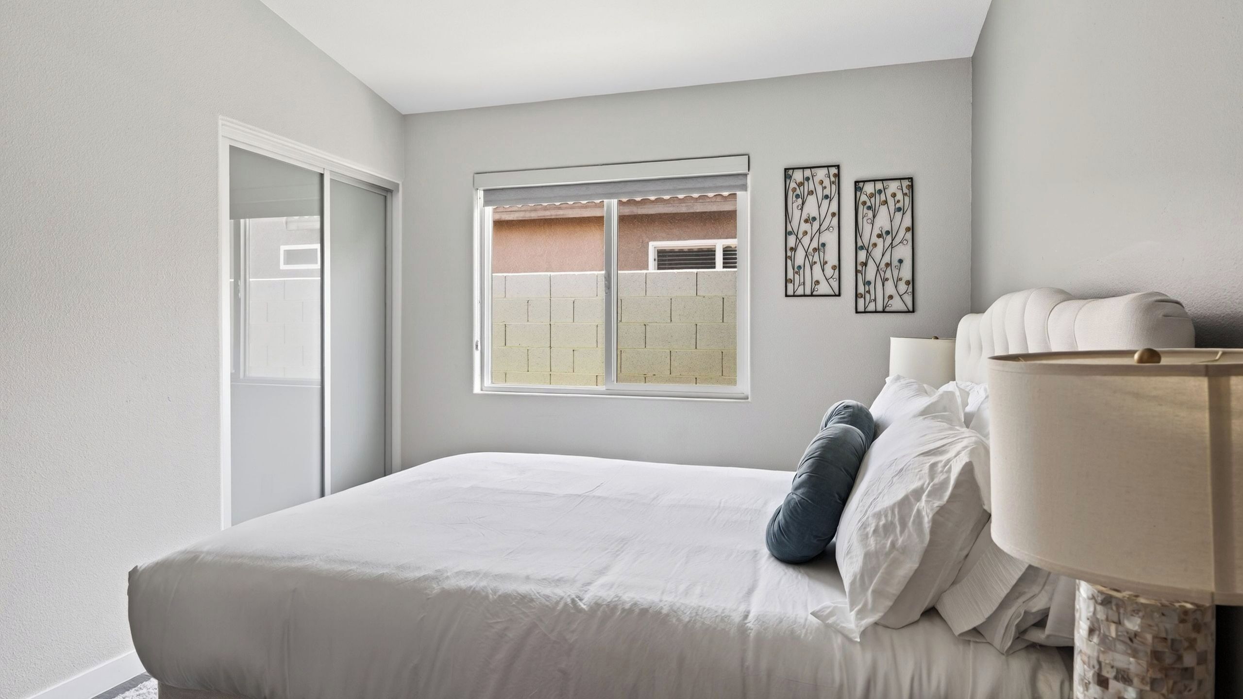 A bedroom with a bed, a window, and two wall art pieces.