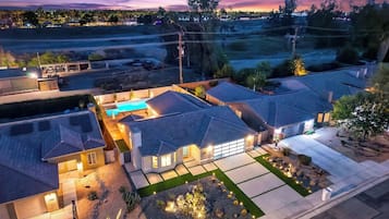 Zona residencial con casas, una piscina y un camino de entrada bien iluminado.