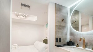 Et moderne hotelværelse med seng, et sminkebord med spejl og en grøn accentvæg.