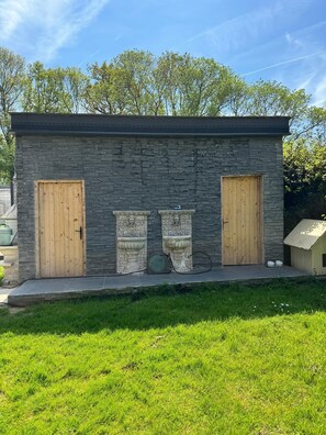 A small stone building with two wooden doors and a small porch area. - Luxury refuge, private estate with XXL heated pool - 6 bedrooms - Normandy (Le Perrey)