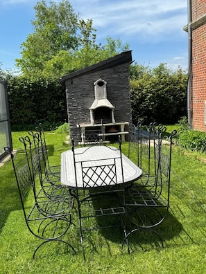 A brick building with a stone facade, a metal table with chairs, and a metal fence. - Luxury refuge, private estate with XXL heated pool - 6 bedrooms - Normandy (Le Perrey)