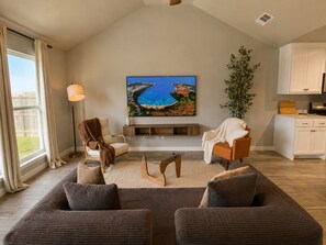 Ein Wohnzimmer mit einem großen Gemälde, einem Sofa, einem Sessel und einer Lampe.