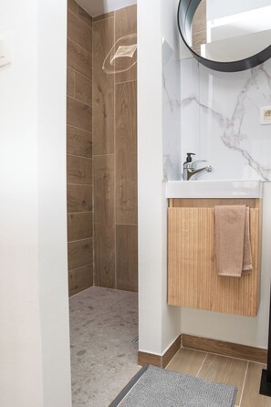 Ein Badezimmer mit Dusche, Waschbecken und Holz-Badmöbel.