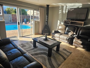 A living room with a sofa, a coffee table, a fireplace, and a TV. - Menza Self-catering in George South Africa- Relaxing Home-away-from Home (George)