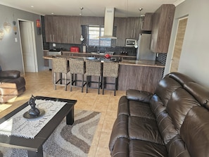 A modern kitchen with a central island, bar stools, a sofa, and a coffee table.