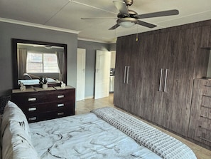 A bedroom with a bed, dresser, wardrobe, ceiling fan, and a view of the outside. - Menza Self-catering in George South Africa- Relaxing Home-away-from Home (George)
