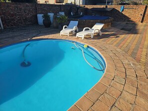 Una piscina con borde azul, rodeada de un patio de ladrillo.