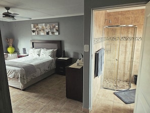 Une chambre à coucher comprenant un lit, une table de chevet, une commode et un espace douche.