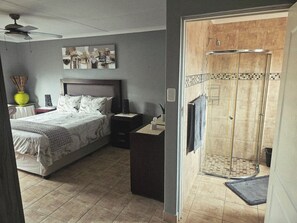 Un dormitorio con cama, mesita de noche y zona de ducha.