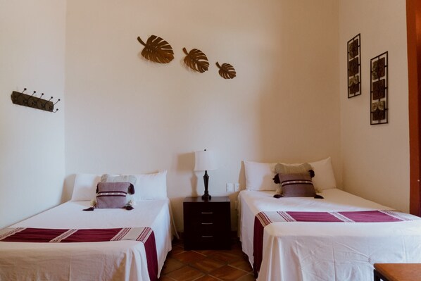 Una habitación de hotel con dos camas, una mesita de noche, una lámpara y adornos en la pared.
