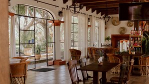 A dining area with a large table and chairs, a bar with bottles, and large windows with a view of trees. - Hacienda San Nicolas de las Fuentes  (Teuchitlán)