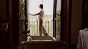A room with a bathtub, a window with a view of greenery, and a balcony with a railing. - Hacienda San Nicolas de las Fuentes  (Teuchitlán)
