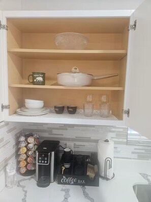 Eine Küche mit einer Kaffeebar, inklusive Kaffeemaschine, Tassen und einer Kanne.