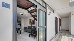 Et moderne interiør med trappe, sofa, sofabord og et køkkenområde.