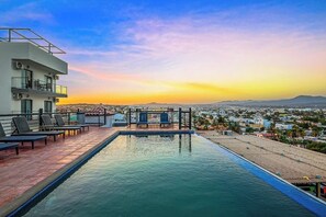 A rooftop pool with lounge chairs and a city view at sunset. - Loft Close to the Ocean With Rooftop Infinity Pool, Balcony & gym - Dog-friendly (Cabo San Lucas)