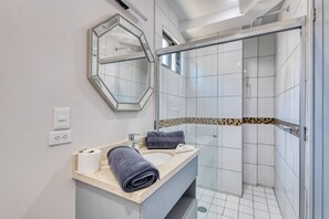 A modern bathroom with a shower, a sink with a mirror, and a towel. - Loft Close to the Ocean With Rooftop Infinity Pool, Balcony & gym - Dog-friendly (Cabo San Lucas)