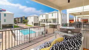 A poolside area with a pool, outdoor seating, and a view of adjacent buildings. - Steps to Beach! Heated Pool & Modern Luxury (gulf shores)