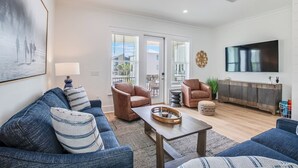 A modern living room with a sofa, armchair, coffee table, and a TV mounted on the wall. - Steps to Beach! Heated Pool & Modern Luxury (gulf shores)