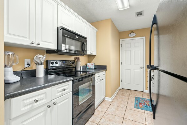 A kitchen with white cabinets, a black stove, a microwave, and a refrigerator. - Private Deck, Foosball, Fire Pit & Grill, Walkable (Auburn)