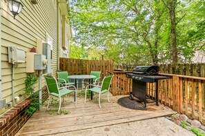 Eine Terrasse mit Grill, grünen Stühlen und einem Tisch.