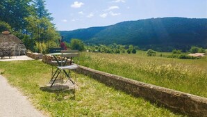 A stone wall, a table with chairs, and a view of a hilly landscape. - For nature lovers, absolute peace and quiet (Peyroules)