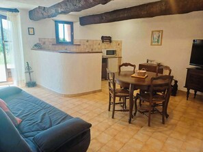A cozy living area with a sofa, dining table, chairs, a TV, and a kitchen area with a microwave. - For nature lovers, absolute peace and quiet (Peyroules)