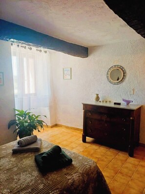 A bedroom with a bed, a dresser, a mirror, a window with curtains, and a potted plant. - For nature lovers, absolute peace and quiet (Peyroules)