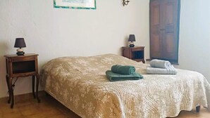 A bedroom with a bed, a nightstand, a lamp, a framed picture, and a door. - For nature lovers, absolute peace and quiet (Peyroules)