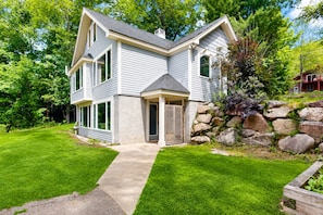 A two-story house with a stone retaining wall, a front porch, and a well-maintained lawn.