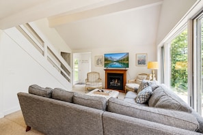 A living room with a large gray sectional sofa, a fireplace, a television, and a staircase.