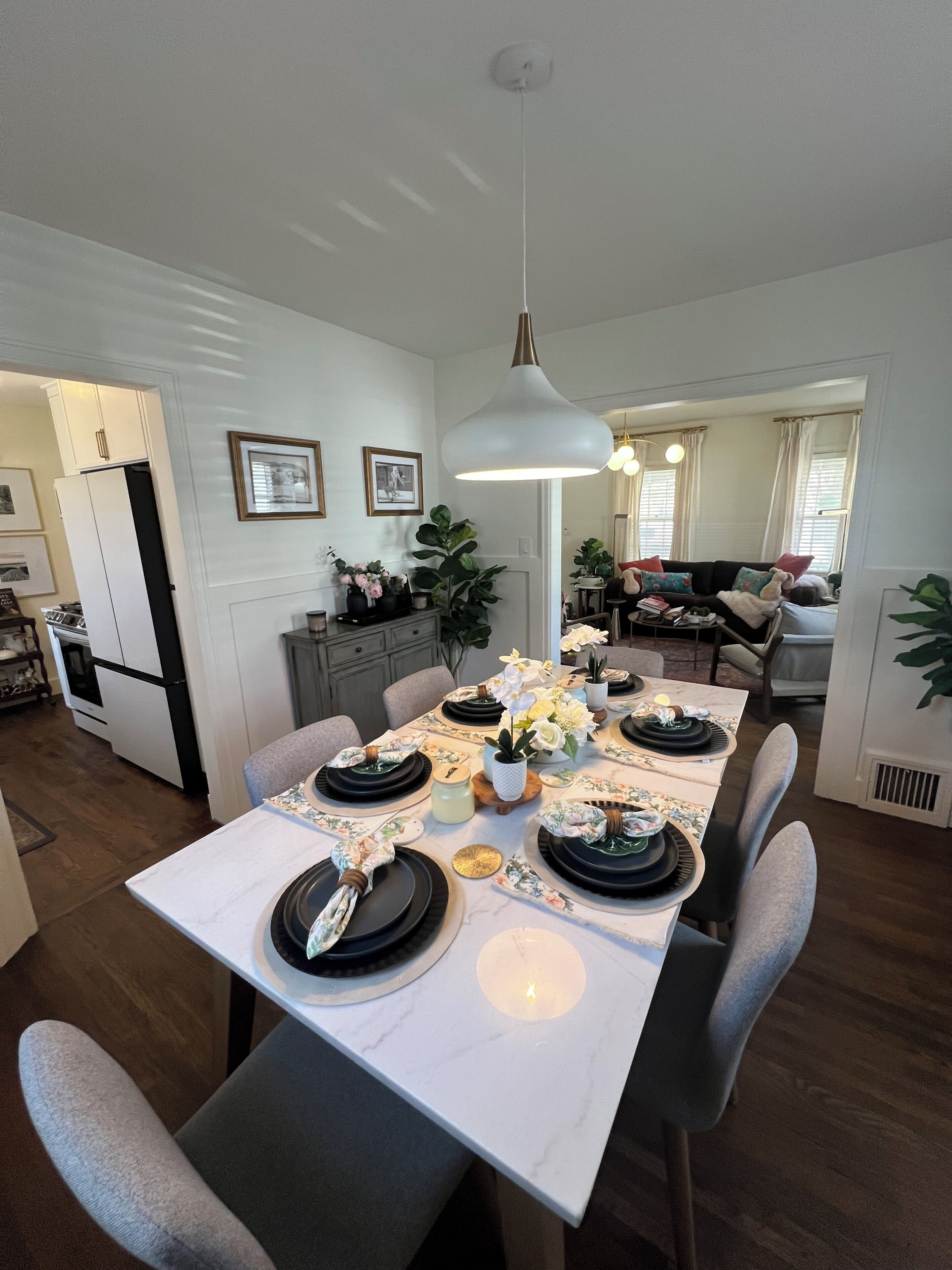 A dining area with a white table set for six, surrounded by grey chairs.