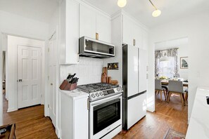 A kitchen with white cabinetry, a stove, microwave, and refrigerator. - Crown Heights Cutie in Perfect Location! (Wichita)