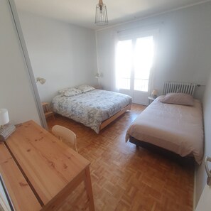 A bedroom with two beds, a wooden table, and a chair. - On the Ile d'Offard in a quiet neighborhood 10 minutes from the town center and train station (Saumur)