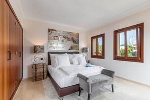 A bedroom with a bed, a chair, a wardrobe, and a painting on the wall.