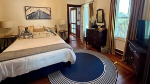 Een slaapkamer met een bed, nachtkastjes, een kaptafel, een spiegel, een televisie en uitzicht op de omgeving.